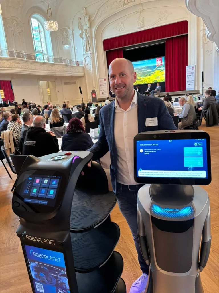 RoboPlanet Head of Sales mit BellaBot Pro und OrionStar Nova auf einer Veranstaltung im Ahrtal