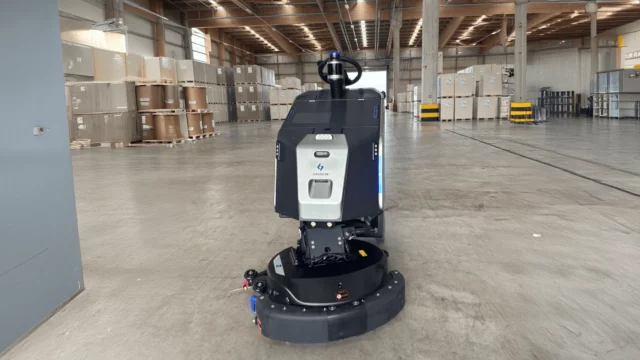 Gausium Scrubber 75 von RoboPlanet in weiterläufiger Industriehalle im Lager