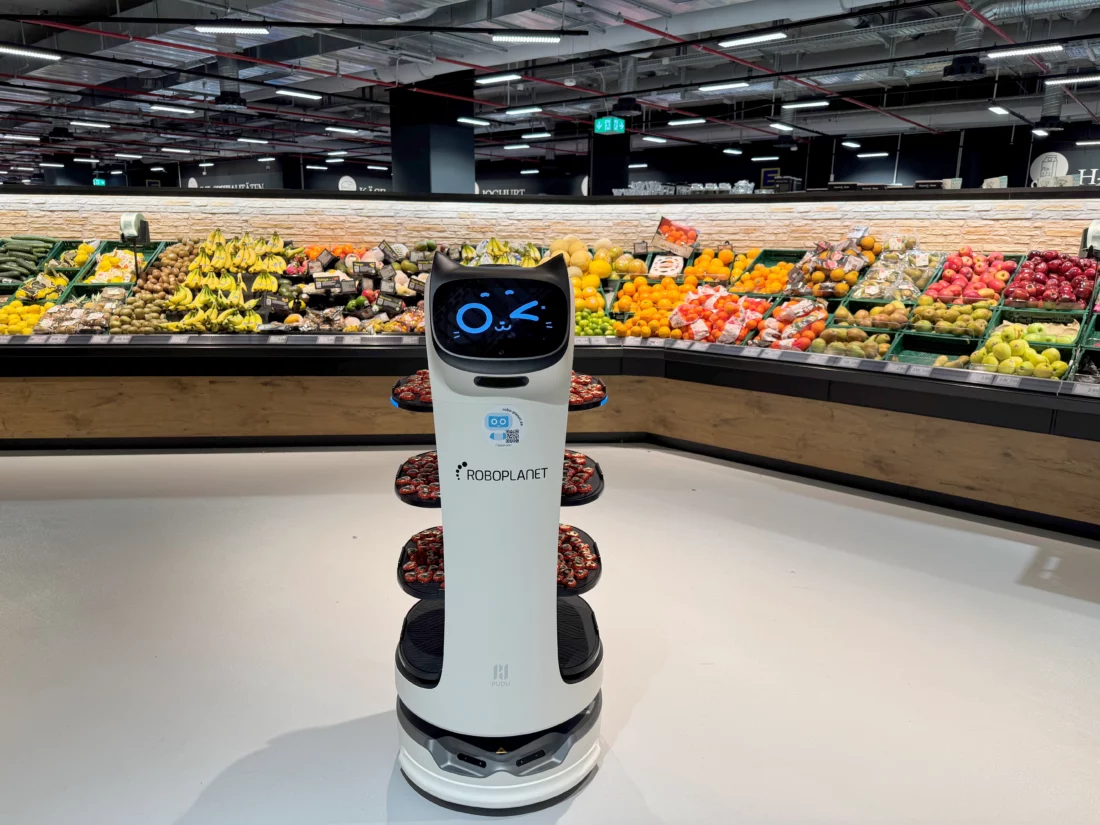 RoboPlanet BellaBot fährt beladen mit Häppchen in einem Edeka herum und wartet vor der Obsttheke auf Abnehmer