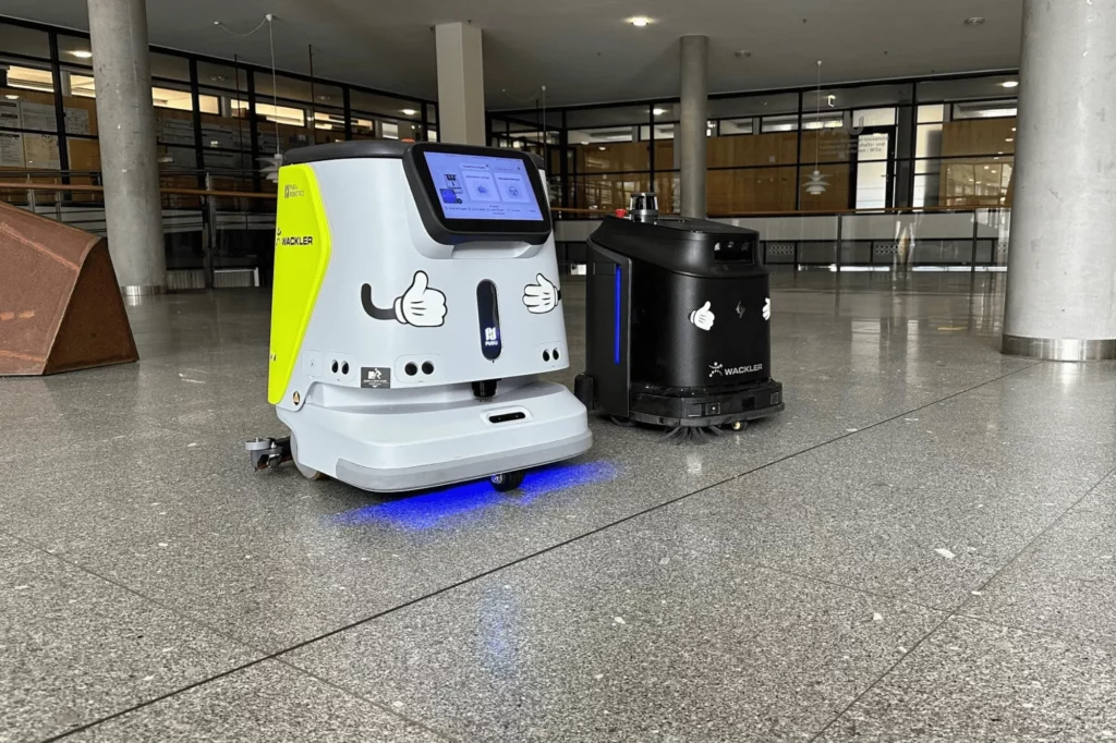 Gausium Phantas und Pudu CC1 mit LED Lichtern in einer großen Eingangshalle auf Marmorboden